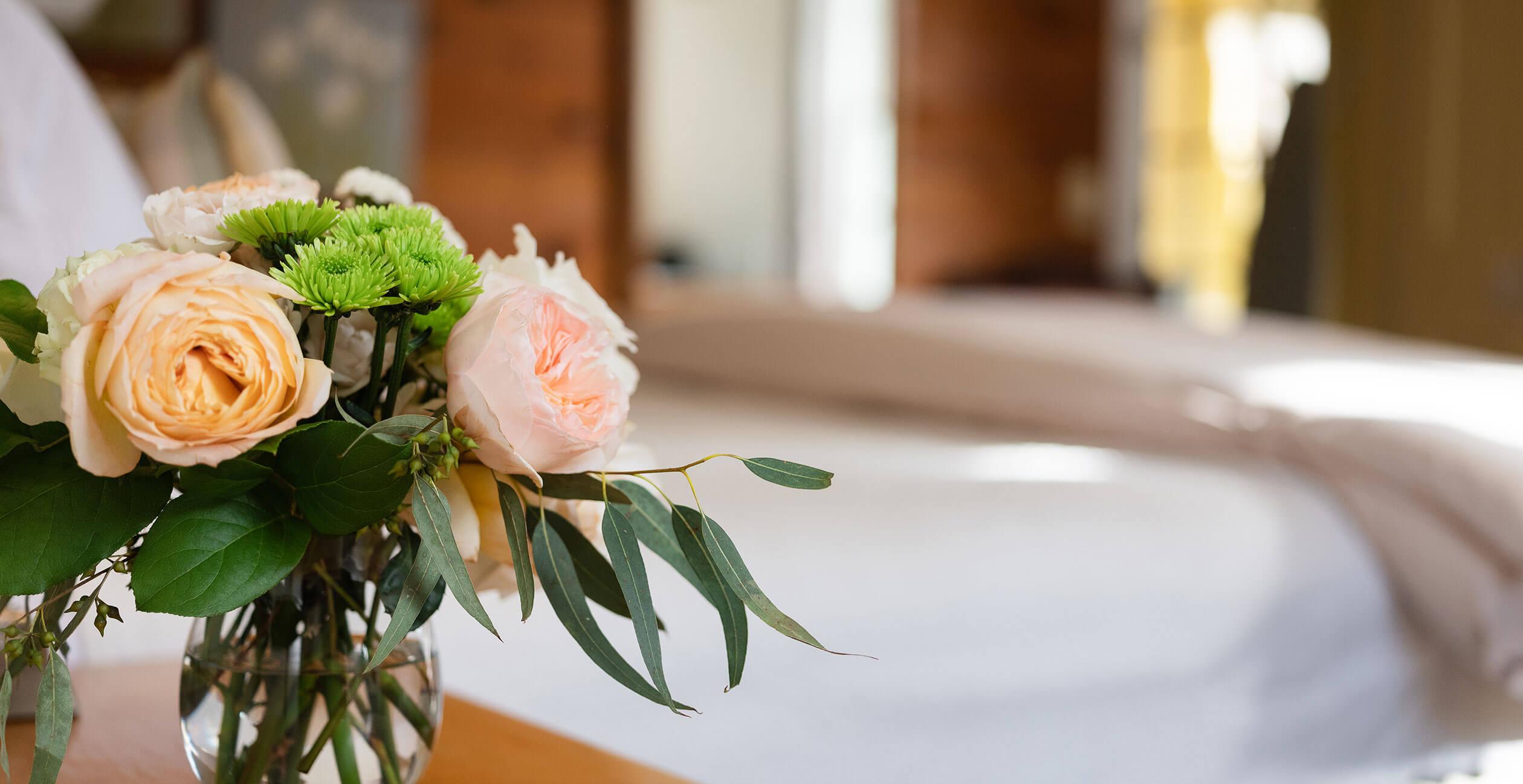 Vase of flowers in front of bed