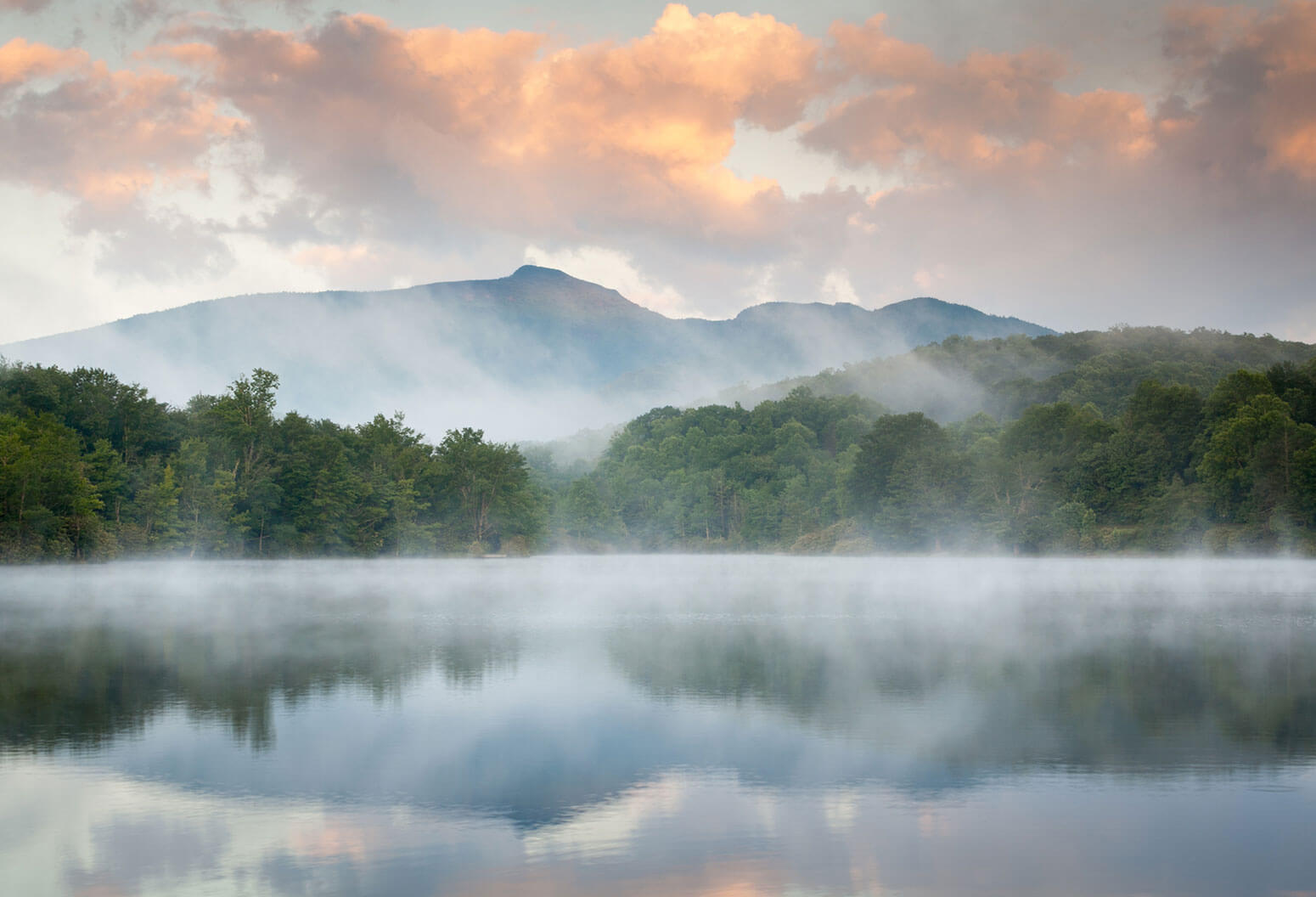 Mountain past foggy lake and forest