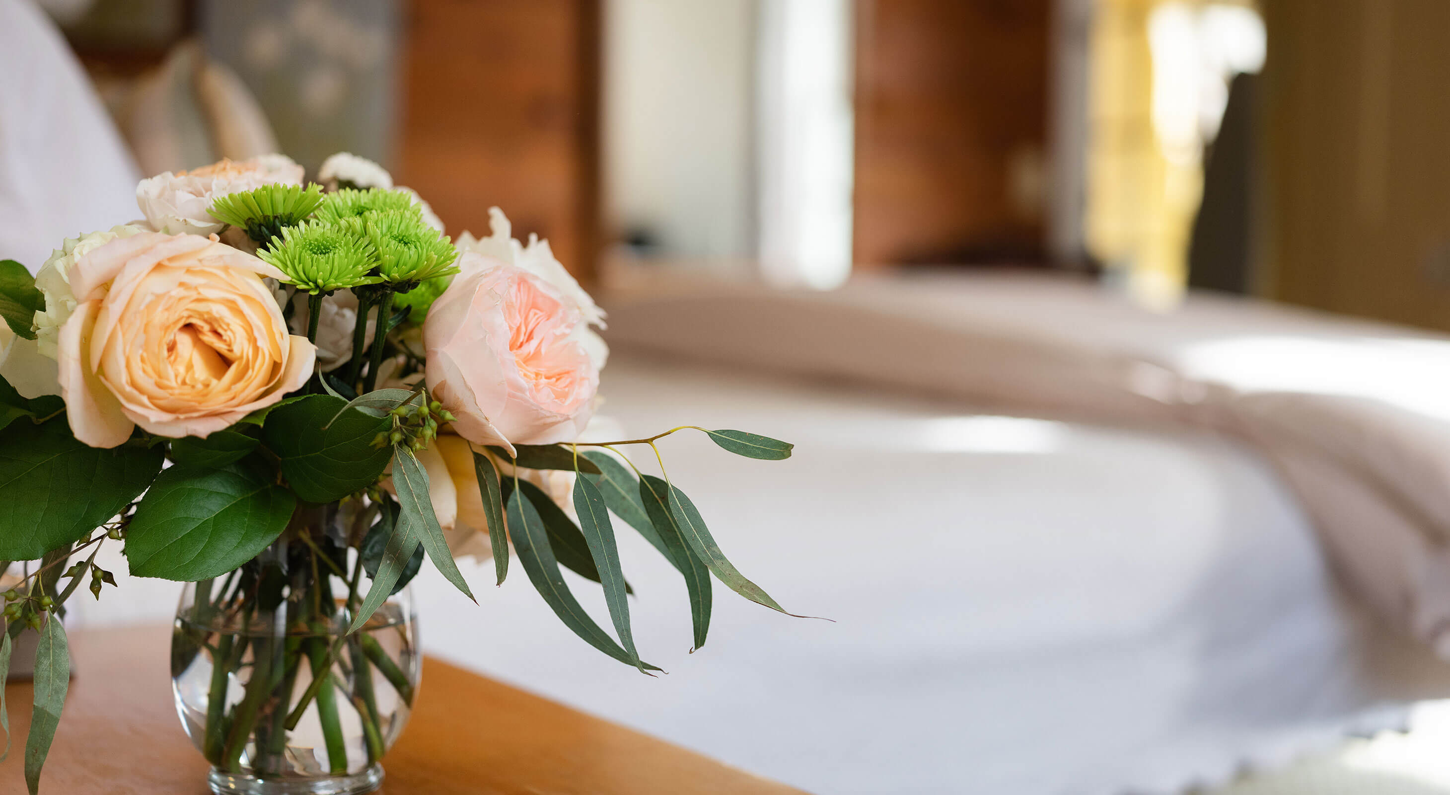 Vase of flowers in front of bed