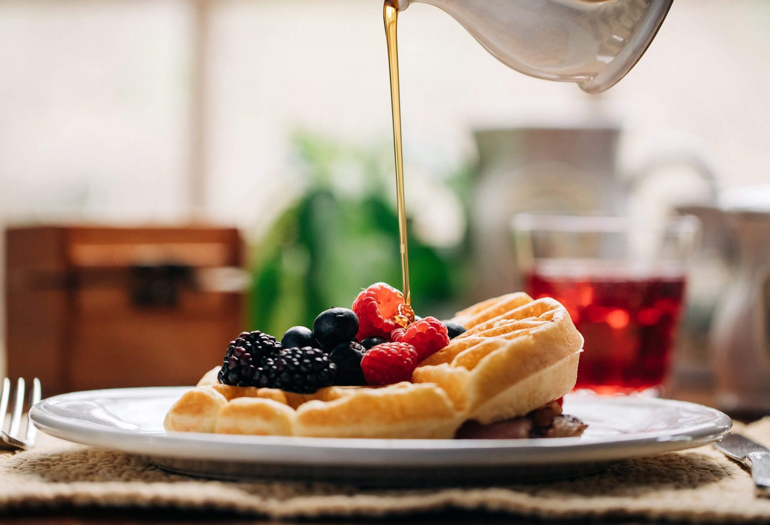 Syrup being poured over a fruit waffle