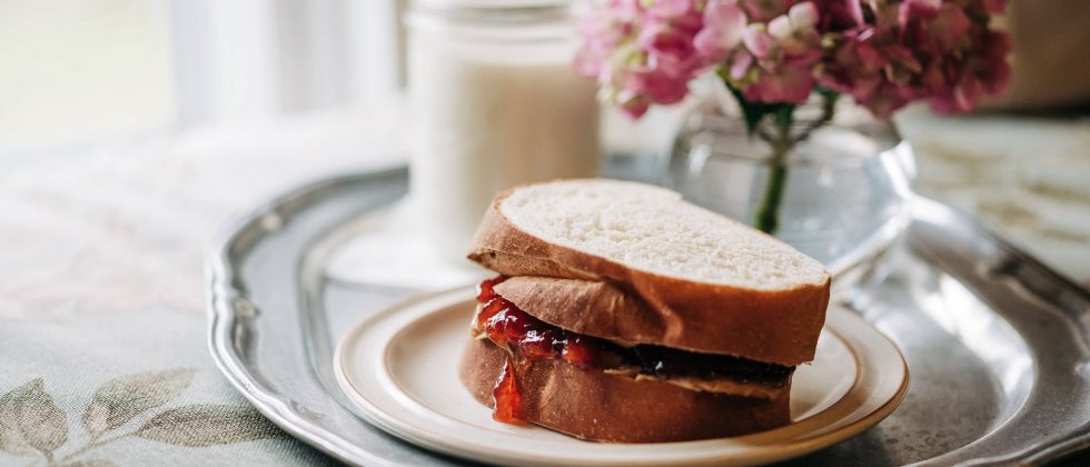 PB&J sandwich on a tray with a glass of milk and flowers