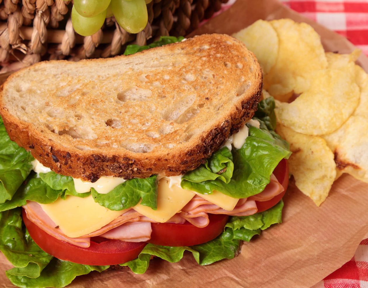 sandwich and chips next to a picnic basket
