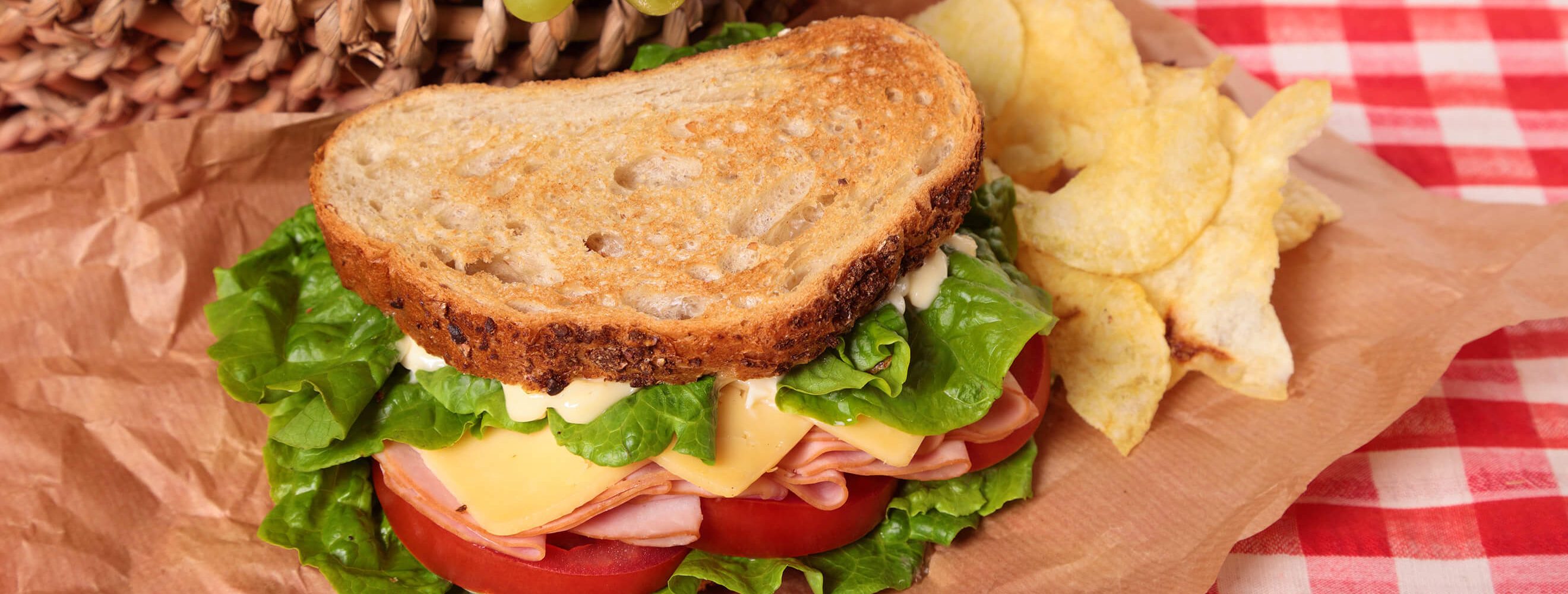 sandwich and chips next to a picnic basket