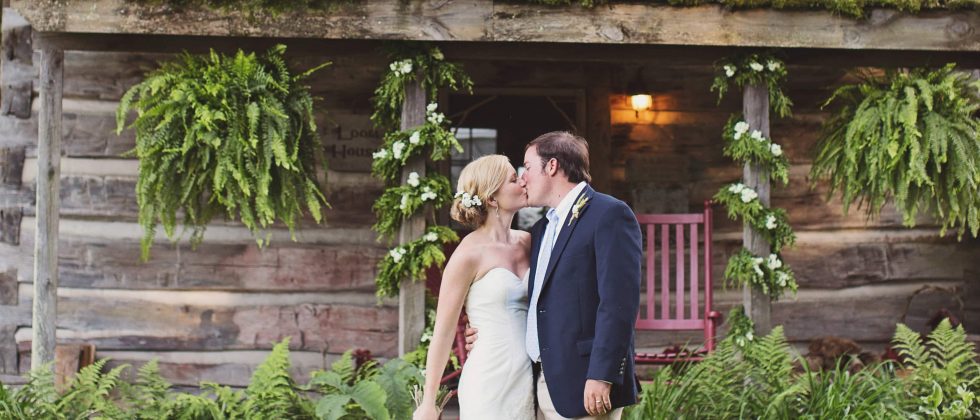 Bride and groom kissing in front of an old cabin