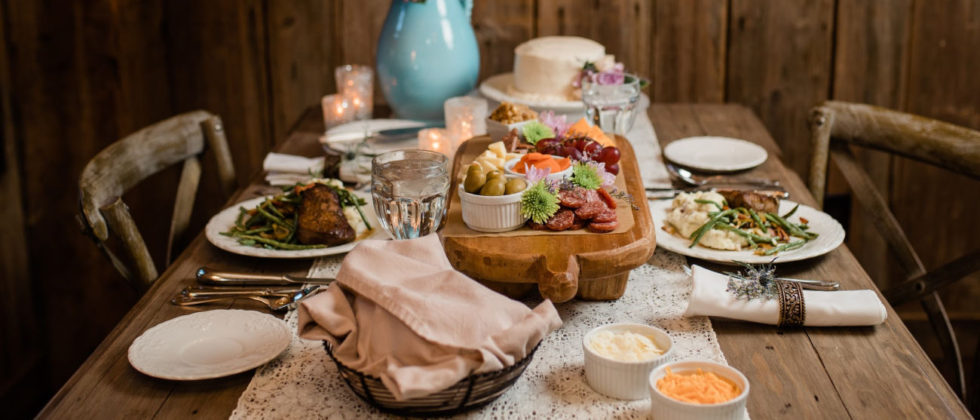 a table set with a bowl of bread and a plate of meats and cheeses