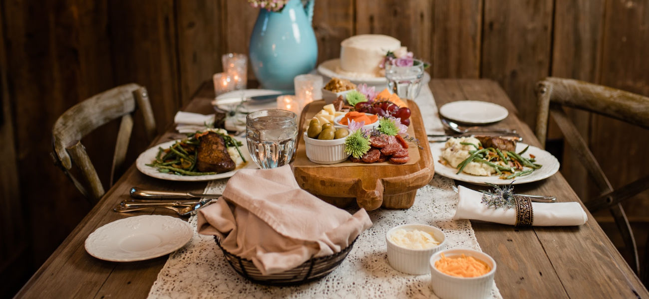 a table set with a bowl of bread and a plate of meats and cheeses