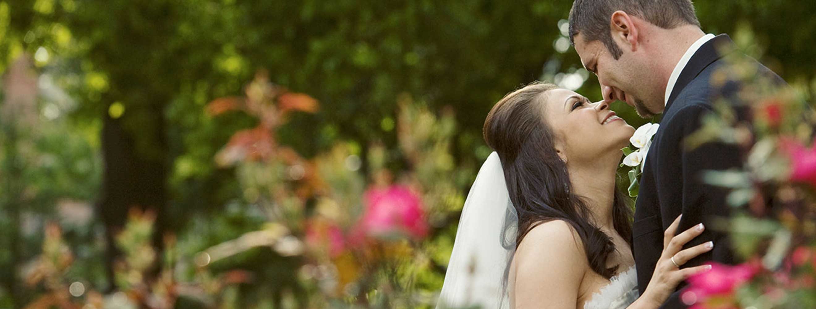 Groom kissing bride in field of pink flowers